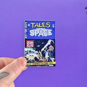 May include: A vintage comic book cover with a blue background and the title "Tales from Space" in yellow letters. The cover features an illustration of a spaceship and people in a futuristic setting. The comic book is titled "Space Zombies from Pluto" and is described as "Shocking Science-Fiction Stories".