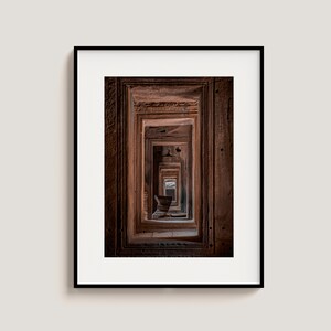 Peut inclure: Une photographie d'un couloir avec de multiples portes, chacune menant &agrave; une autre porte. Les portes sont en pierre et sont toutes de la m&ecirc;me taille. Le couloir est sombre et la lumi&egrave;re au bout du couloir est &agrave; peine visible.