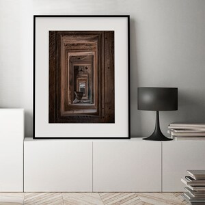 Peut inclure: Une photographie encadr&eacute;e d'un couloir avec de multiples portes, chacune avec des sculptures complexes. Les portes sont dispos&eacute;es dans une perspective qui cr&eacute;e un sentiment de profondeur et de myst&egrave;re.