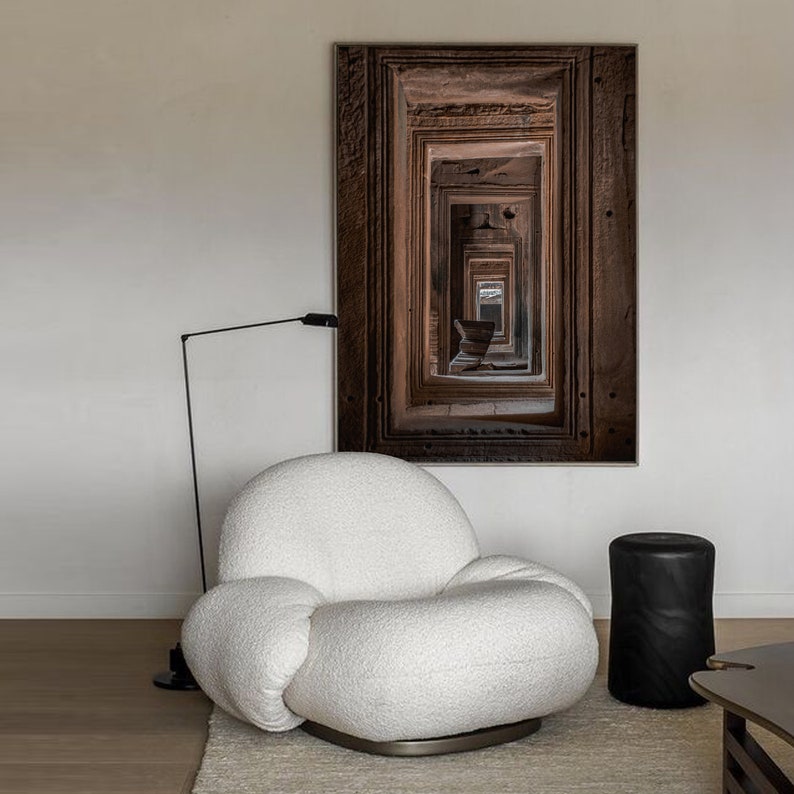 Peut inclure: Un fauteuil blanc moelleux et arrondi, de forme organique, est plac&eacute; dans un salon moderne. Un lampadaire noir se trouve derri&egrave;re le fauteuil, et une estampe encadr&eacute;e noire et brune est accroch&eacute;e au mur derri&egrave;re le fauteuil. L'estampe pr&eacute;sente un motif r&eacute;p&eacute;titif de portes.