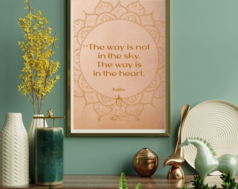 May include: A framed print with a gold border displays a Buddha quote: "The way is not in the sky. The way is in the heart." The print has a peach background with a mandala design. The image is part of a home decor display.