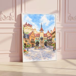 May include: A framed watercolor painting depicting a European town square with cobblestone ground, multi-story buildings with orange roofs, a central clock tower, and a bright blue sky with white clouds. The scene features hanging flower baskets.