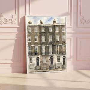 May include: A framed watercolor painting depicting a row of multi-story brick townhouses with dark doors, white window frames, and black iron railings. The architecture features a classic urban design with multiple levels of windows under a blue sky.