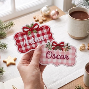 Pode incluir: Duas etiquetas de nome bordadas personalizadas com bordas recortadas. Uma etiqueta apresenta um padrão xadrez vermelho e branco com o nome Arthur em escrita branca. A outra tem um padrão xadrez rosa claro com o nome Oscar em rosa escuro.