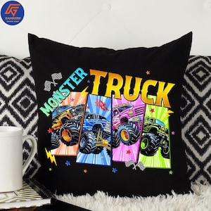 May include: Black throw pillow featuring a colorful graphic of four monster trucks. The pillow has the words "MONSTER TRUCK" in a vibrant design. Each truck is a different color, with checkered flags and stars.