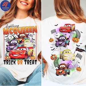May include: A white t-shirt featuring a graphic print of Lightning McQueen and other characters from the movie Cars. The design includes Halloween elements like pumpkins, spider webs, bats, and the text Lightning McQueen Trick or Treat.
