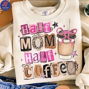 May include: Cream-colored sweatshirt with the text "Half Mom Half Coffee" in a collage style. The design includes pink, brown, and leopard print accents, along with a coffee cup graphic with a pink bow and a straw. A black star and pink star accents are also included.