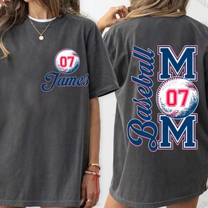 May include: Two gray t-shirts with a baseball theme. One shirt has a baseball with the number 07 and the name "James" printed on it. The other shirt has the word "Baseball" and the word "MOM" with a baseball and the number 07 printed on it.