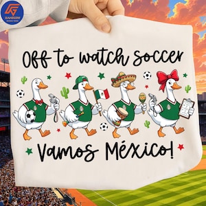 May include: A white t-shirt featuring the text "Off to watch soccer" and "VAMOS MÉXICO!" with a graphic of four cartoon ducks wearing green soccer jerseys, holding items like a soccer ball, a Mexican flag, a maraca, a whistle, and a clipboard.