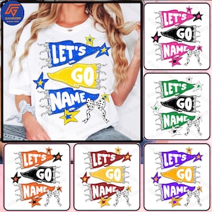 May include: White t-shirt with a colorful graphic design featuring the words "LET'S GO NAME" on pennant banners. The design includes stars and a bow with a polka dot pattern. The shirt is a casual style.