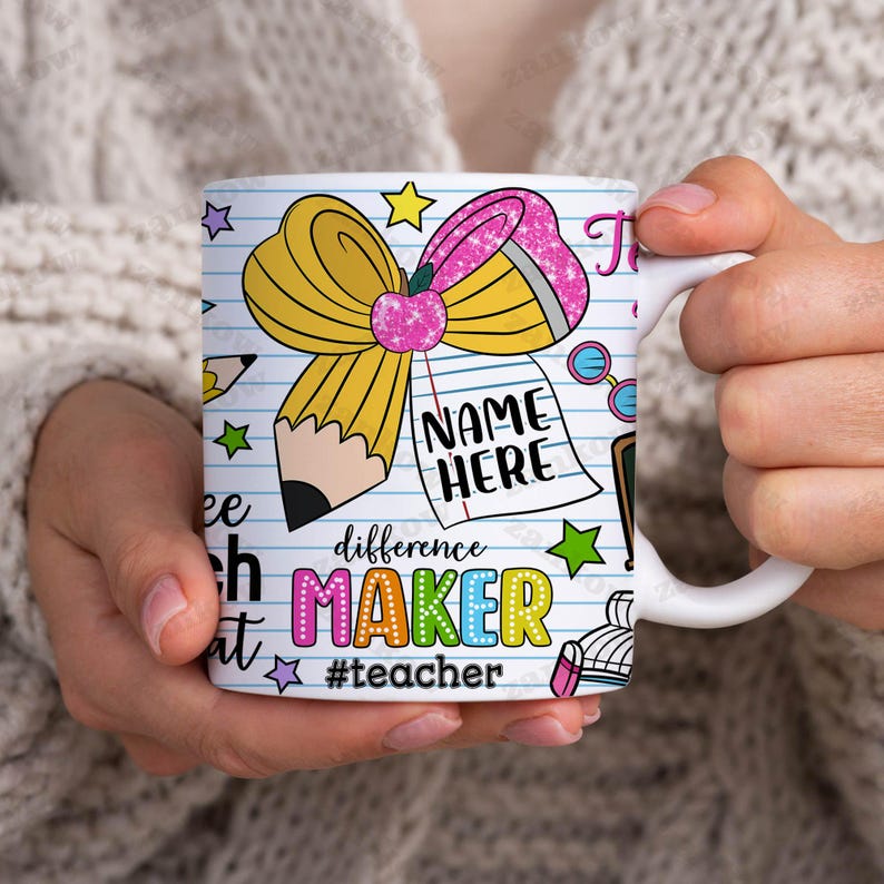 May include: White ceramic mug with a colorful design featuring a yellow pencil bow, a notepad that says "NAME HERE", and the words "difference MAKER #teacher". The mug is held by a person.