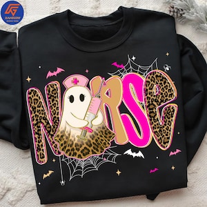 May include: Black sweatshirt with a Halloween-themed design. The word "NURSE" is displayed in a combination of leopard print, pink, and tan colors. A ghost character wearing a nurse's hat and holding a syringe is in the center of the design.