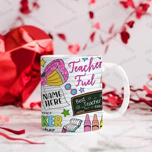 May include: White ceramic mug with a colorful design featuring the text "Teacher Fuel" and various school-themed illustrations. The mug includes a blackboard with the text "Best Teacher ever" and a space for a name.