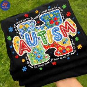 Puede incluir: Sudadera negra con un diseño de pieza de rompecabezas colorido y la palabra "AUTISMO". Las piezas del rompecabezas están decoradas con bordados florales y la frase "No te cambiaría por el mundo, pero cambiaría el mundo por ti."