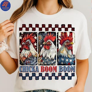 Può includere: T-shirt bianca con una grafica di tre galli con creste rosse e colori patriottici. I galli sono posti su uno sfondo di stelle e strisce. Il testo "CHICKA BOOM BOOM" è visualizzato sotto.