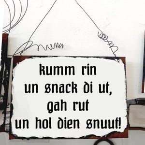 Puede incluir: Un letrero de metal blanco con texto negro que dice "kumm rin un snack di ut, gah rut un hol dien snuut!"