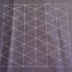 May include: A dark blue fabric with a white geometric pattern of triangles arranged in a grid. The pattern is hand-drawn with visible lines, creating a textured appearance. The overall design is a simple, yet visually interesting pattern.