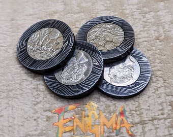 May include: A collection of five round coasters with a silver coin design set into a patterned, dark gray and black wood grain. The word "Enigma" is displayed in colorful, stylized text.