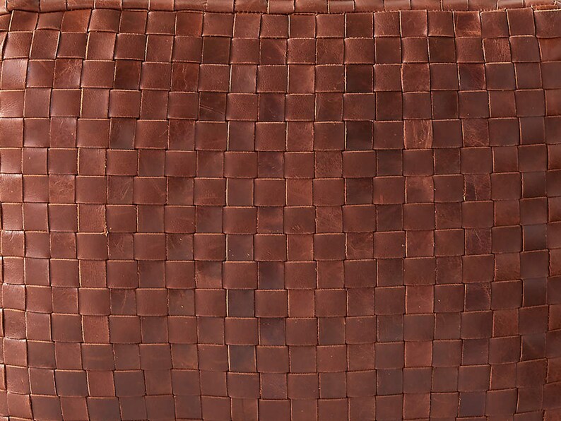 May include: A brown leather surface featuring a tight, uniform woven grid pattern. The material displays natural variations in tone and texture across the interlocking square strips, creating a consistent, dense, and tactile geometric design.