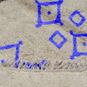 Alfombra Beni Ourain, de lana marroquí anudada a mano, color marfil con formas geométricas azules. imagen 3