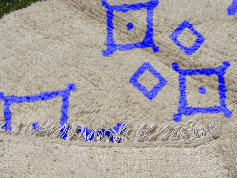 Alfombra Beni Ourain, de lana marroquí anudada a mano, color marfil con formas geométricas azules. imagen 3