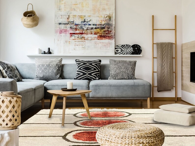 May include: A rectangular area rug featuring a cream-coloured base with dark brown horizontal lines and three prominent, textured, circular motifs in shades of deep red and orange, positioned centrally on the floor in a living room setting.