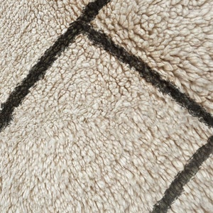 May include: A high-pile rug featuring a thick, cream-colored shag texture with dark brown, hand-drawn geometric lines intersecting across the surface. The dense, soft fibers create a deep, plush appearance with a visible grid pattern.