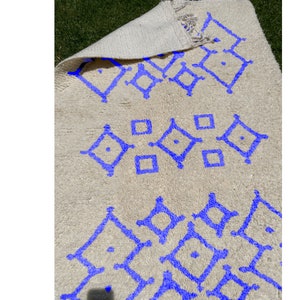 Alfombra Beni Ourain, de lana marroquí anudada a mano, color marfil con formas geométricas azules. imagen 2