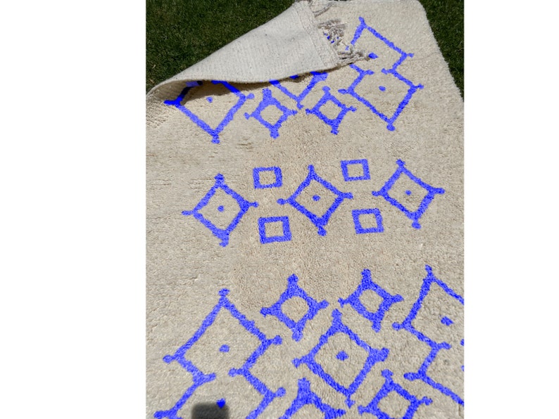 Alfombra Beni Ourain, de lana marroquí anudada a mano, color marfil con formas geométricas azules. imagen 2