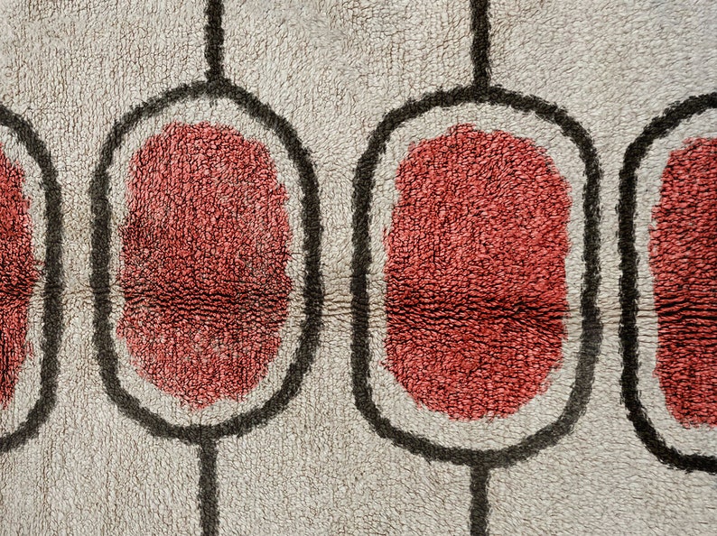 May include: A textured rug featuring a repeating pattern of vertical black lines connecting rounded rectangular shapes. Each shape contains a solid, deep red centre surrounded by a light grey, plush, high-pile fabric background.
