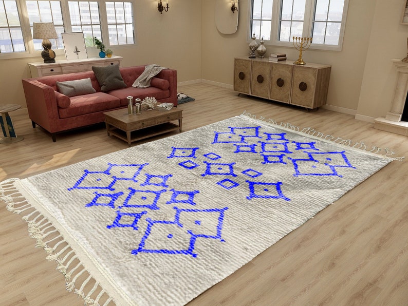 Alfombra Beni Ourain, de lana marroquí anudada a mano, color marfil con formas geométricas azules. imagen 1