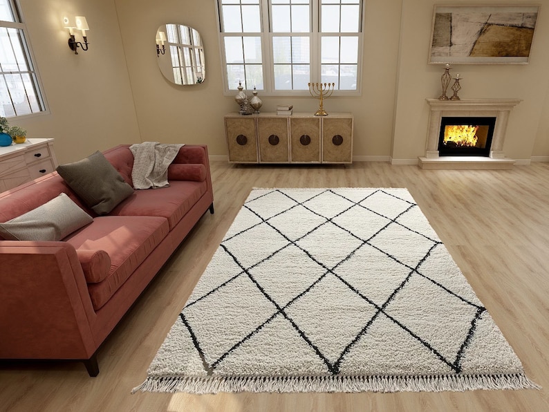 May include: A rectangular area rug featuring a cream-colored shaggy pile with a repeating black diamond grid pattern. The rug is finished with short, straight fringe along the edges, providing a textured surface for the living room floor.