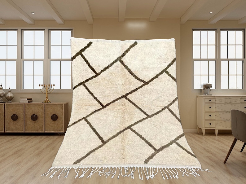 May include: A rectangular area rug featuring a cream-colored base with a dark brown geometric grid pattern of intersecting lines. The rug has a thick, textured pile and is finished with long, white fringe tassels along the bottom edge.