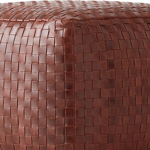 May include: A square-shaped ottoman featuring a rich, dark brown exterior constructed from tightly woven strips of material. The surface displays a consistent, uniform grid pattern created by the interlocking weave, covering the top and sides.