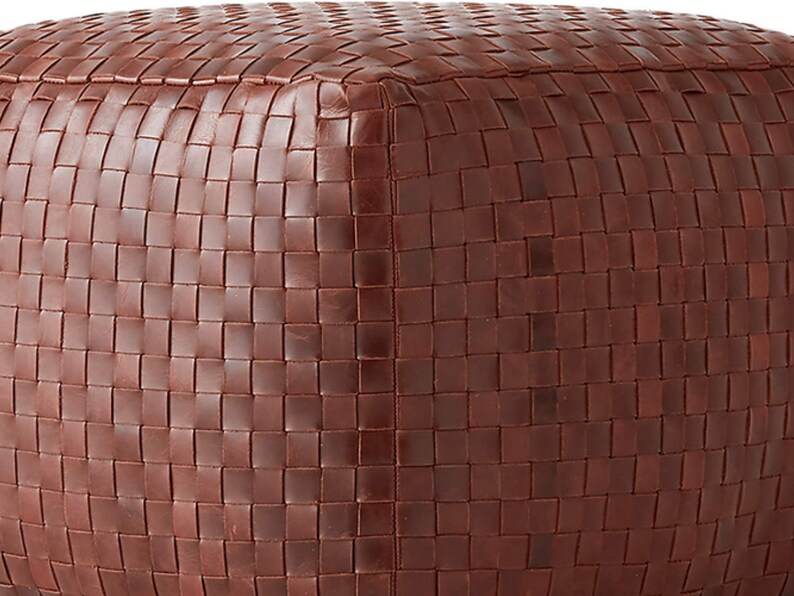 May include: A square-shaped ottoman featuring a rich, dark brown exterior constructed from tightly woven strips of material. The surface displays a consistent, uniform grid pattern created by the interlocking weave, covering the top and sides.