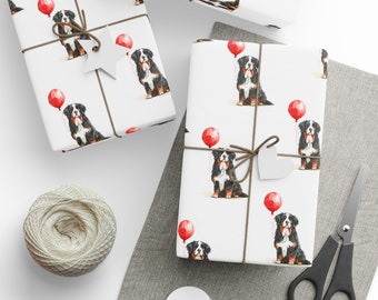 May include: White wrapping paper with a repeating pattern of Bernese Mountain Dogs holding red balloons. The paper is tied with a brown ribbon and a white heart-shaped tag.