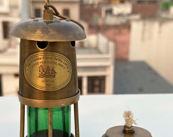 Op de afbeelding: Antieke messing Permissible Flame Safety Lamp met een groene glazen cilinder en een afneembare bovenkant. De lamp is gemarkeerd met "MADE FOR ROYAL NAVY LONDON 1920". De lamp is ontworpen met een handvat en een kleine lus om op te hangen.