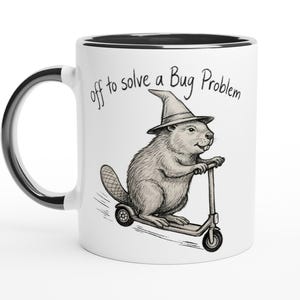 Könnte beinhalten: Weiße Keramiktasse mit schwarzem Rand und Griff. Die Tasse zeigt eine skurrile Illustration eines Bibers mit Hexenhut, der einen Roller fährt, mit dem Text "off to solve a Bug Problem."