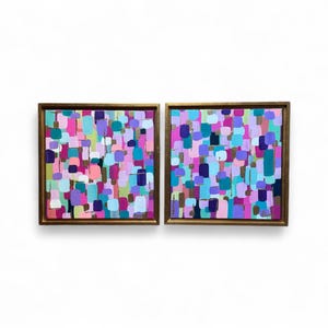 Peut inclure: Deux peintures abstraites encadr&eacute;es avec une bordure dor&eacute;e. Chaque peinture pr&eacute;sente un arrangement color&eacute; de coups de pinceau dans des tons de rose, de violet, de bleu et de vert. L'&oelig;uvre est expos&eacute;e sur un fond blanc.