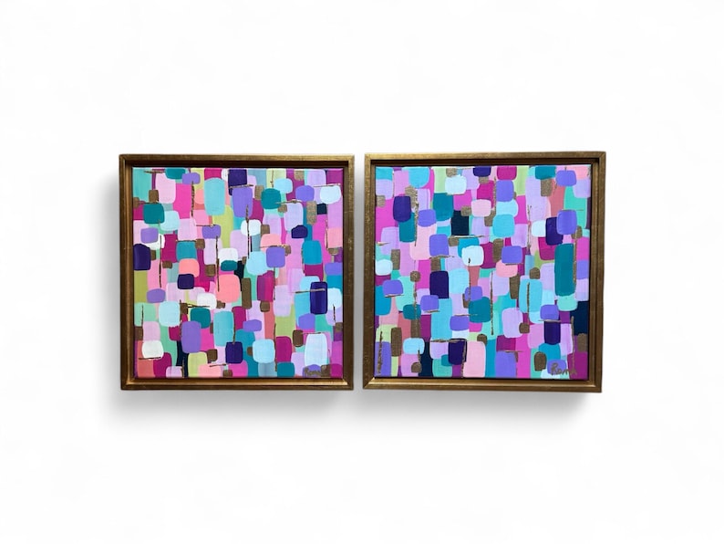 Peut inclure: Deux peintures abstraites carr&eacute;es avec des cadres dor&eacute;s. Chaque &oelig;uvre pr&eacute;sente un arrangement color&eacute; de formes rectangulaires dans des tons de rose, de violet, de bleu et d'or. Les peintures sont expos&eacute;es sur un fond blanc.