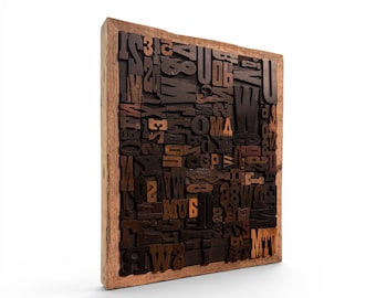 May include: A wooden framed print block filled with various dark brown wooden letterpress letters and numbers. The letters and numbers are arranged in a seemingly random pattern, creating a textured surface. The frame is a light brown color.