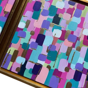 Peut inclure: Peinture d'art abstrait avec un cadre dor&eacute;. L'&oelig;uvre pr&eacute;sente un motif color&eacute; de coups de pinceau dans des tons de rose, de violet, de sarcelle et d'or. La peinture est carr&eacute;e et semble &ecirc;tre sur toile.