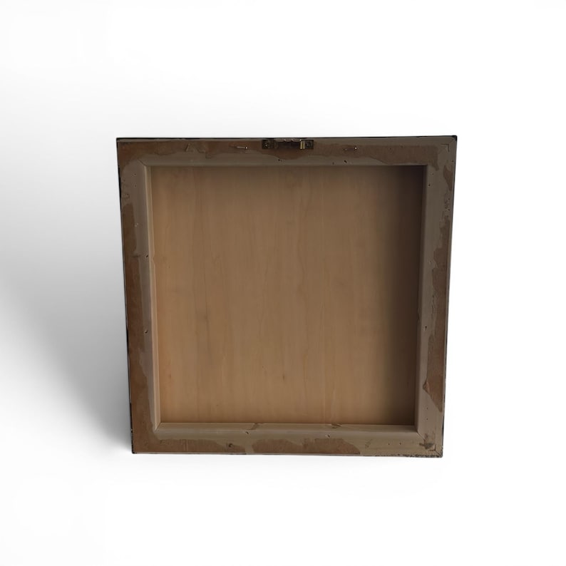 May include: Back view of a square wooden framed art piece. The frame is a dark color with a lighter, distressed edge. The back of the artwork is a light brown wood, with a metal hanger attached at the top.