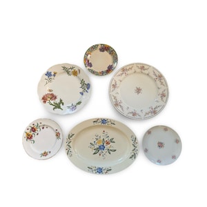 May include: A collection of vintage floral patterned plates and serving dishes. The set includes various sizes and shapes, featuring colorful flower designs on a white background. The arrangement includes a large oval platter and several round plates.