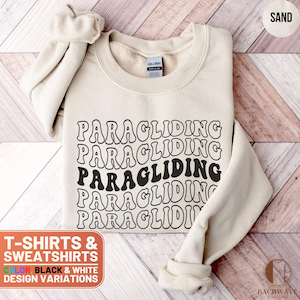 May include: A beige sweatshirt with the text "PARAGLIDING" repeated five times in a retro font. The text is black and the sweatshirt is made of a soft, comfortable material. T-shirts & Sweatshirts. Color: Black & White. Design Variations.