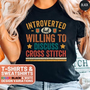 May include: Black t-shirt with a vintage-style graphic that reads "Introverted but willing to discuss cross stitch".