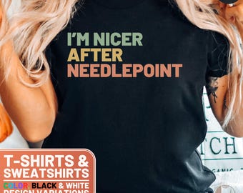 May include: Black t-shirt with the text "I'M NICER AFTER NEEDLEPOINT" in a retro color scheme. The text is in a bold, sans-serif font. The shirt is available in black and white.