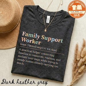 May include: Dark heather grey t-shirt with the text "Family Support Worker" in colorful letters. The shirt includes a definition and description of the role. A gold necklace and a straw hat are also visible.