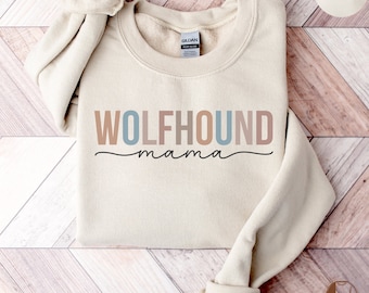 May include: Sand-colored sweatshirt with the text "WOLFHOUN mama" in a mix of colors. The sweatshirt is made of a soft material and has a crew neck. The image also includes the word "SAND" in a circle.