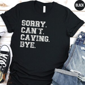 May include: Black t-shirt with white text that reads "Sorry. Can't. Caving. Bye."